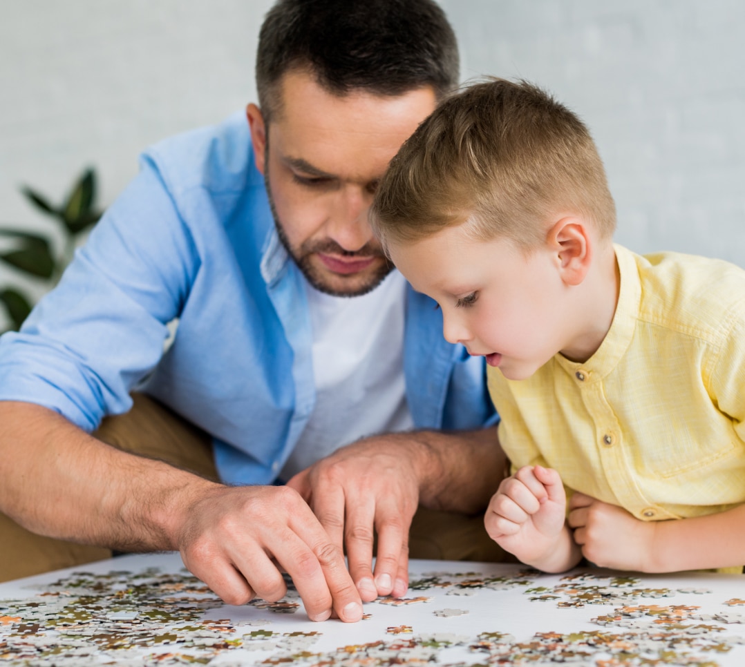 focused-father-and-son-playing-with-jigsaw-puzzle-2023-11-27-05-25-42-utc